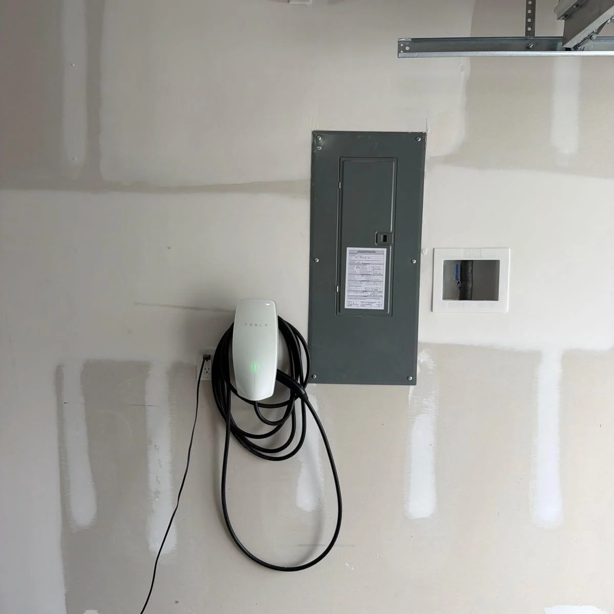 Garage wall with an electrical panel and wall-mounted electric vehicle charger, shown on Logan's public business profile.